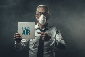 Man with mask pointing to "fresh air" sign